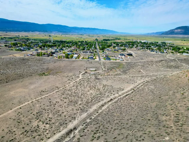 Expansive undeveloped land featuring natural desert vegetation, a long unpaved road, and distant mountain ranges