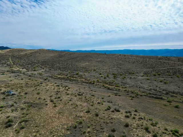 Expansive arid landscape featuring natural vegetation and distant hills
