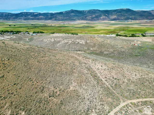 Expansive rural landscape featuring distant mountains, a green valley, and an unpaved road