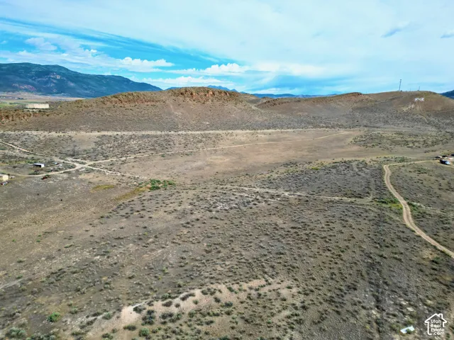 Expansive undeveloped land featuring natural desert vegetation, rolling hills, and distant mountain ranges