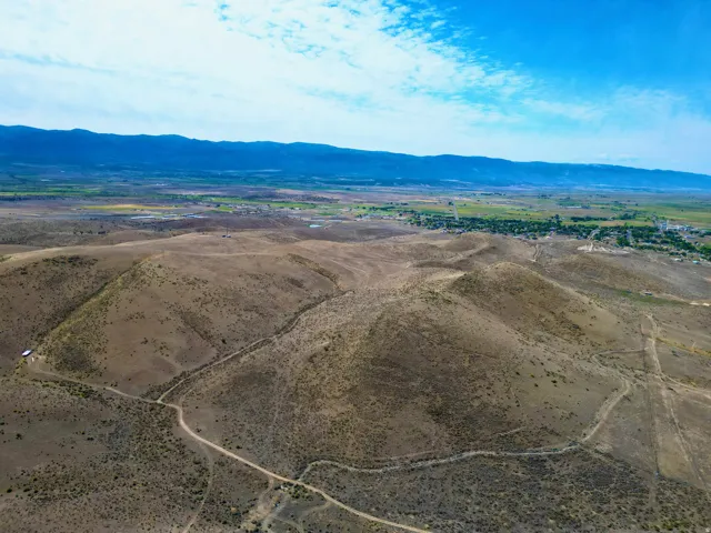 Expansive desert landscape featuring rolling hills and distant green valleys