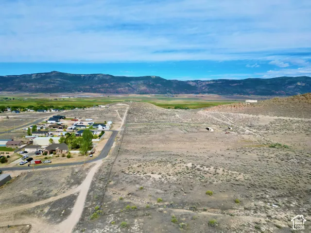 Expansive undeveloped land featuring natural desert vegetation, unpaved roads, and distant mountain ranges