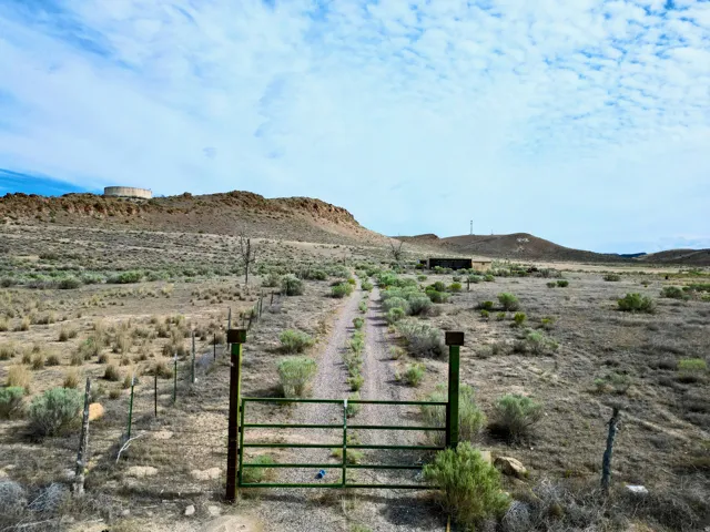 Gated property entrance with a dirt road extending into the distance, framed by natural desert flora