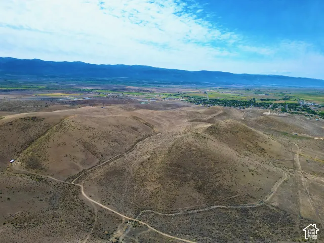 Expansive desert landscape featuring rolling hills and distant green valleys