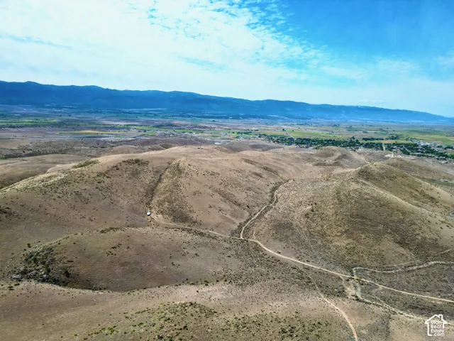 Expansive arid landscape featuring rolling hills and distant mountainous terrain
