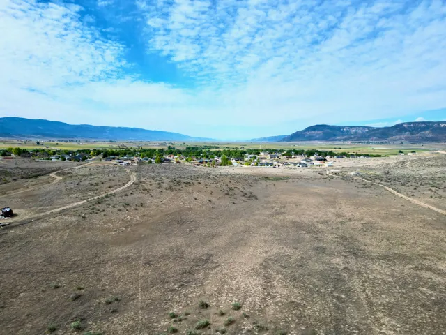 Expansive undeveloped terrain with distant residential structures and mountain ranges