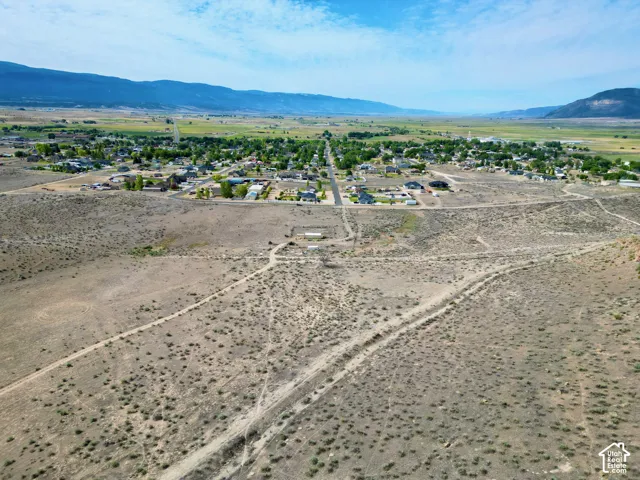 Expansive undeveloped land featuring natural desert vegetation, a long unpaved road, and distant mountain ranges
