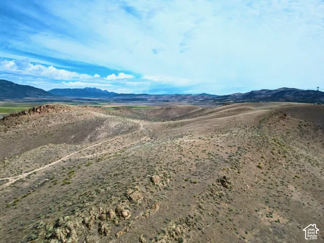 Expansive undeveloped land featuring rolling hills, natural rock formations, sparse vegetation, and distant mountain ranges