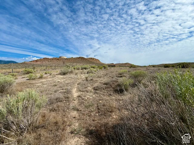 Expansive land parcel featuring natural desert vegetation, a visible dirt path, and distant rocky hills under a broad sky