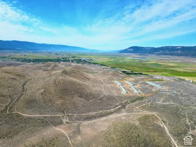 Expansive rural land featuring multiple agricultural structures, a network of unpaved roads, and distant mountainous terrain