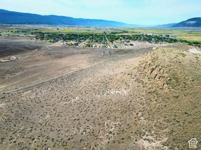 Expansive arid terrain featuring a prominent rocky outcrop and distant mountain ranges