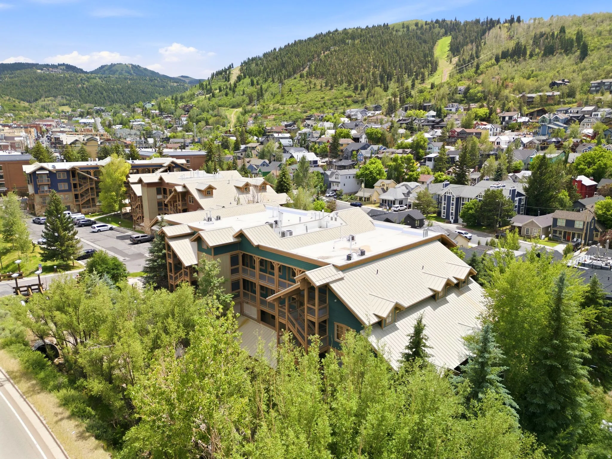 Aerial perspective showcasing a multi-story building with a light-colored metal roof and green siding