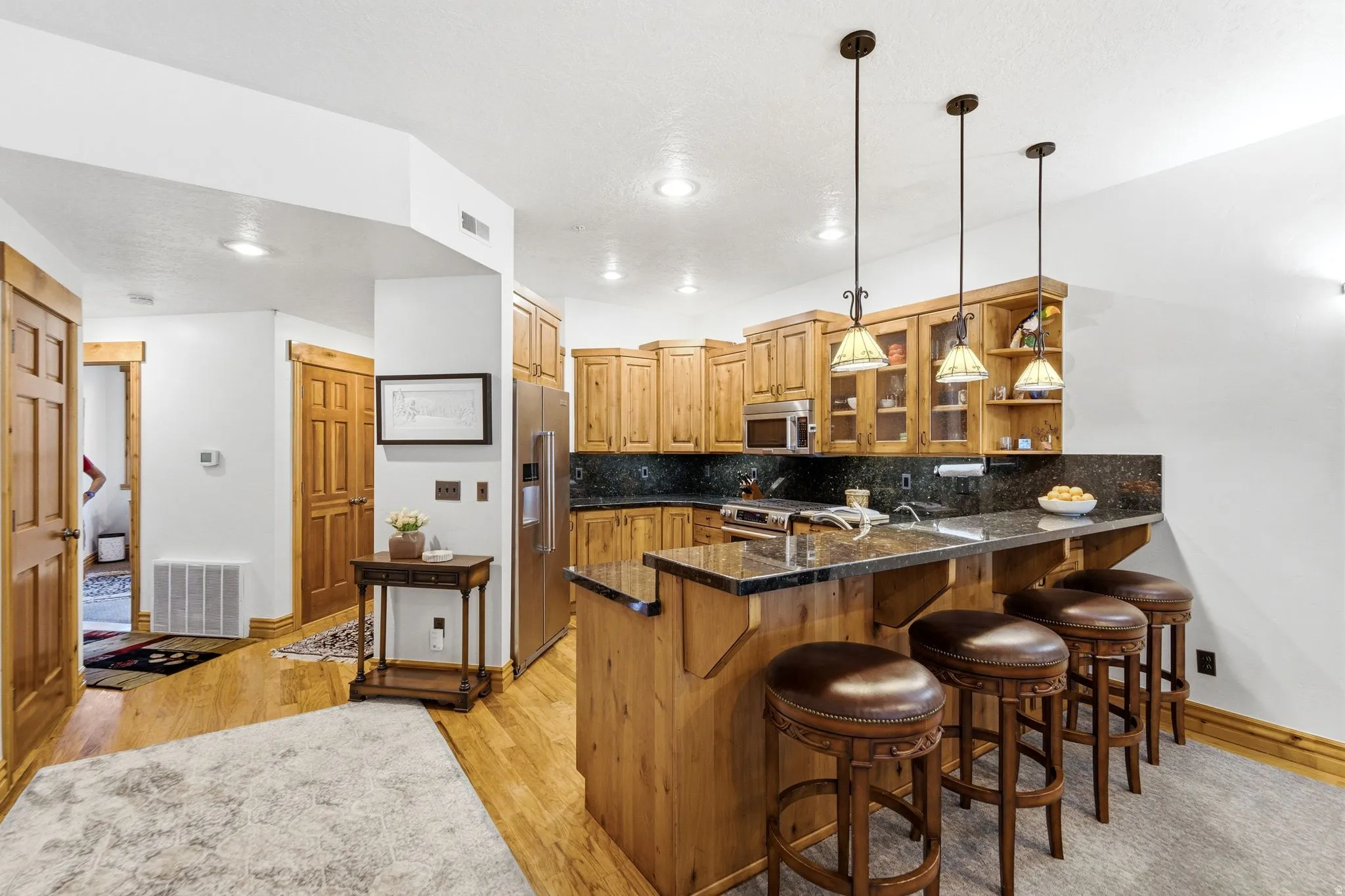 Kitchen area featuring light wood cabinetry, dark stone countertops, and stainless steel appliances