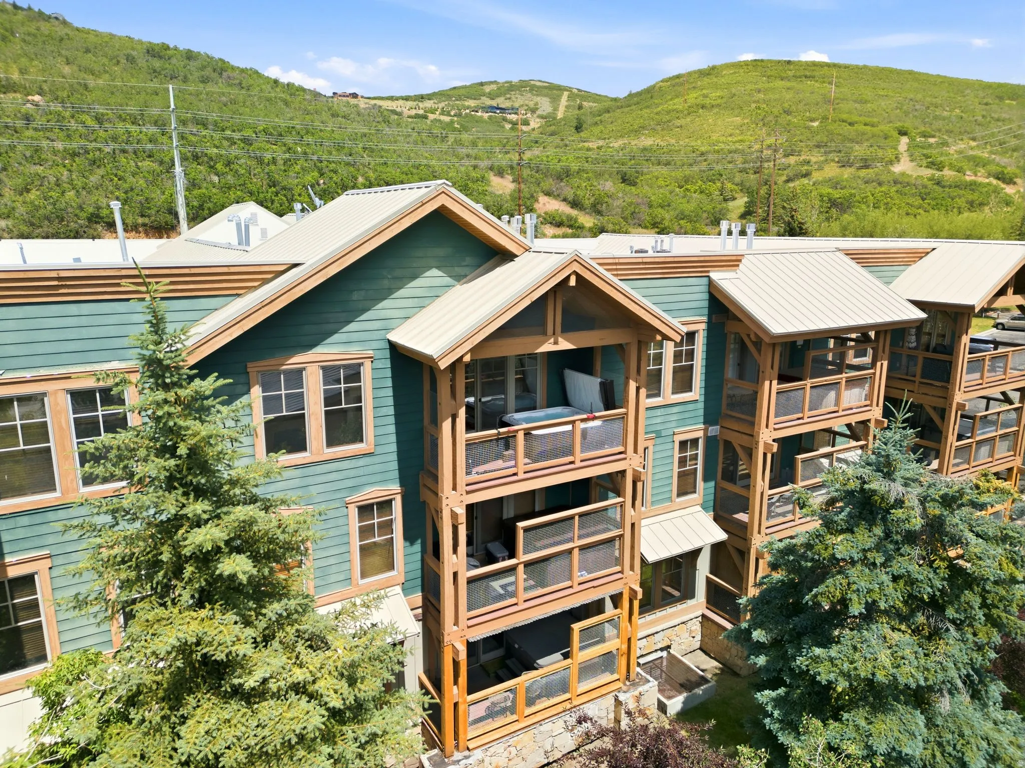 Multi-level property featuring green siding, natural wood-finish accents, and multiple private balconies