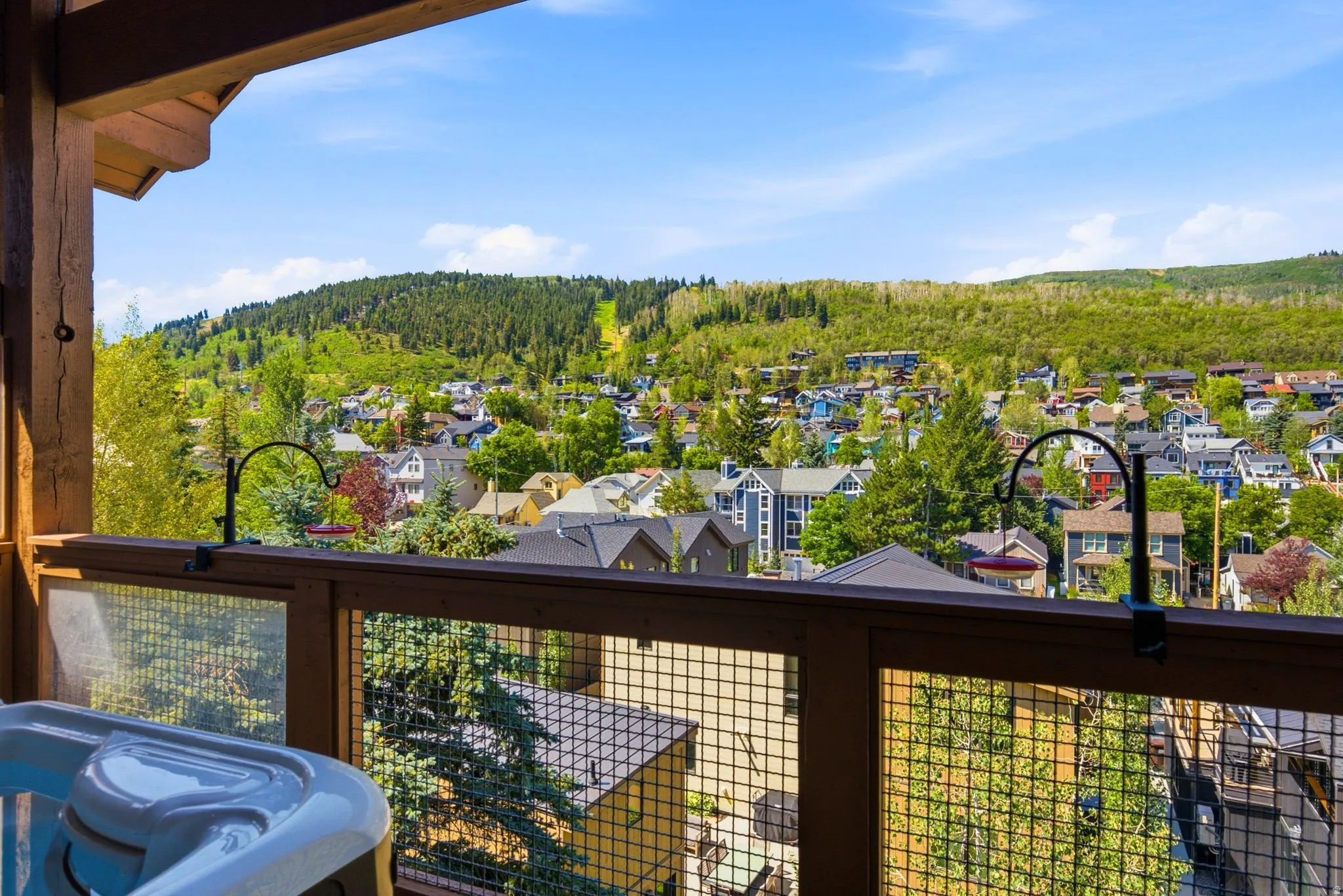 Outdoor deck featuring a built-in spa, wood beam construction, and mesh railing panels