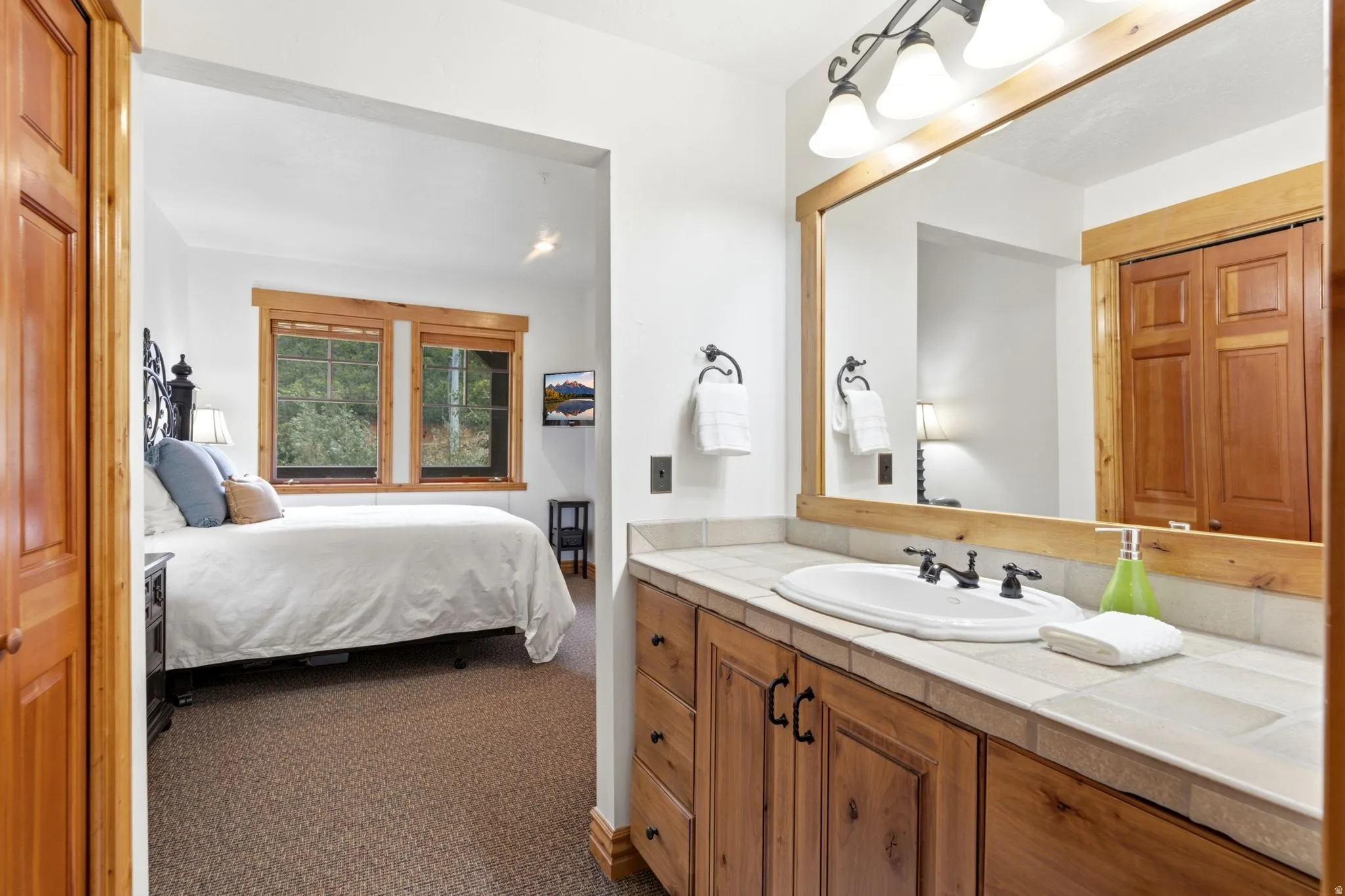 Bathroom vanity with wood-finish cabinetry, tile countertop, and a framed mirror