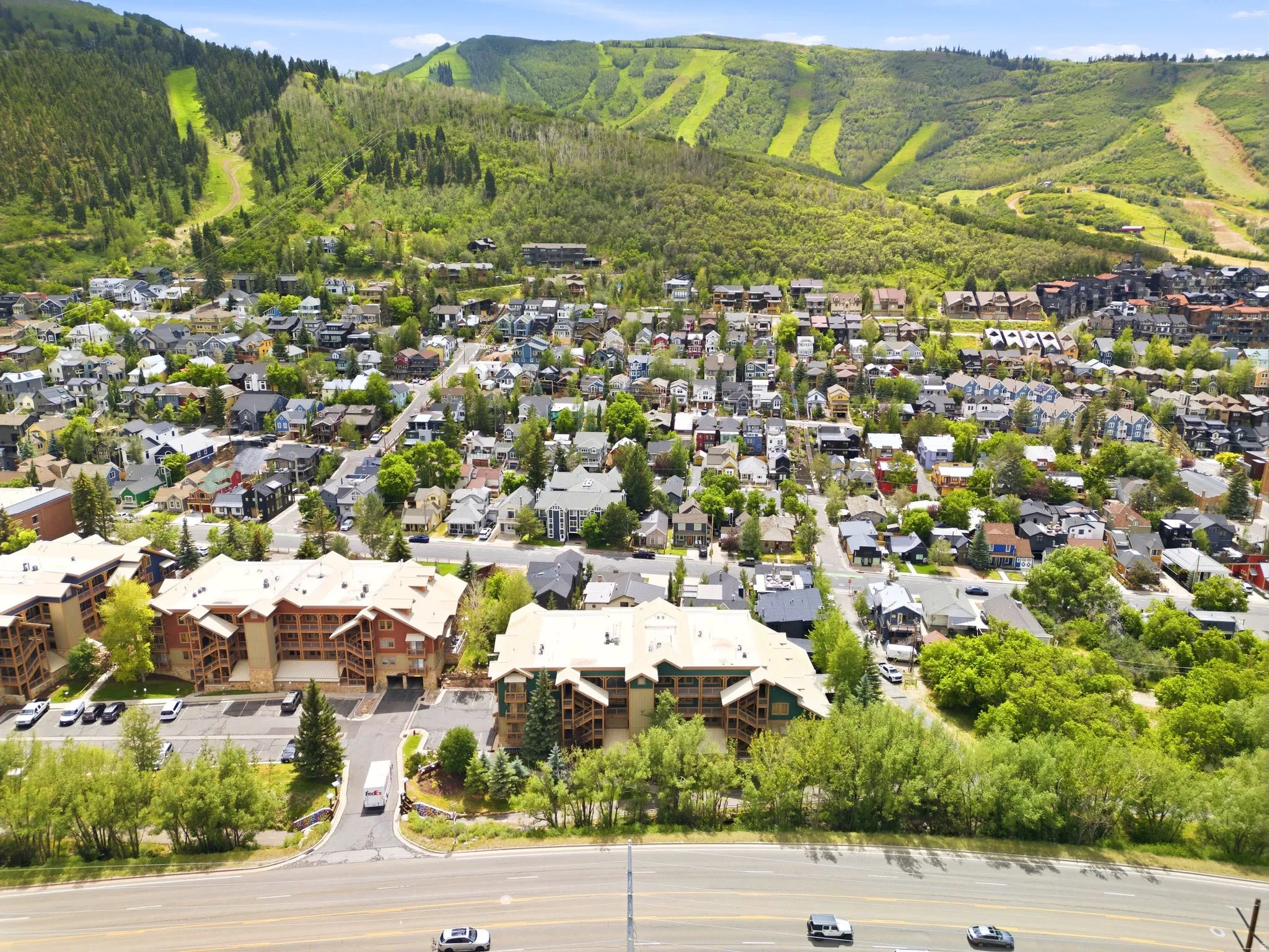 Aerial perspective showcasing a community nestled at the base of a forested mountain with visible ski runs