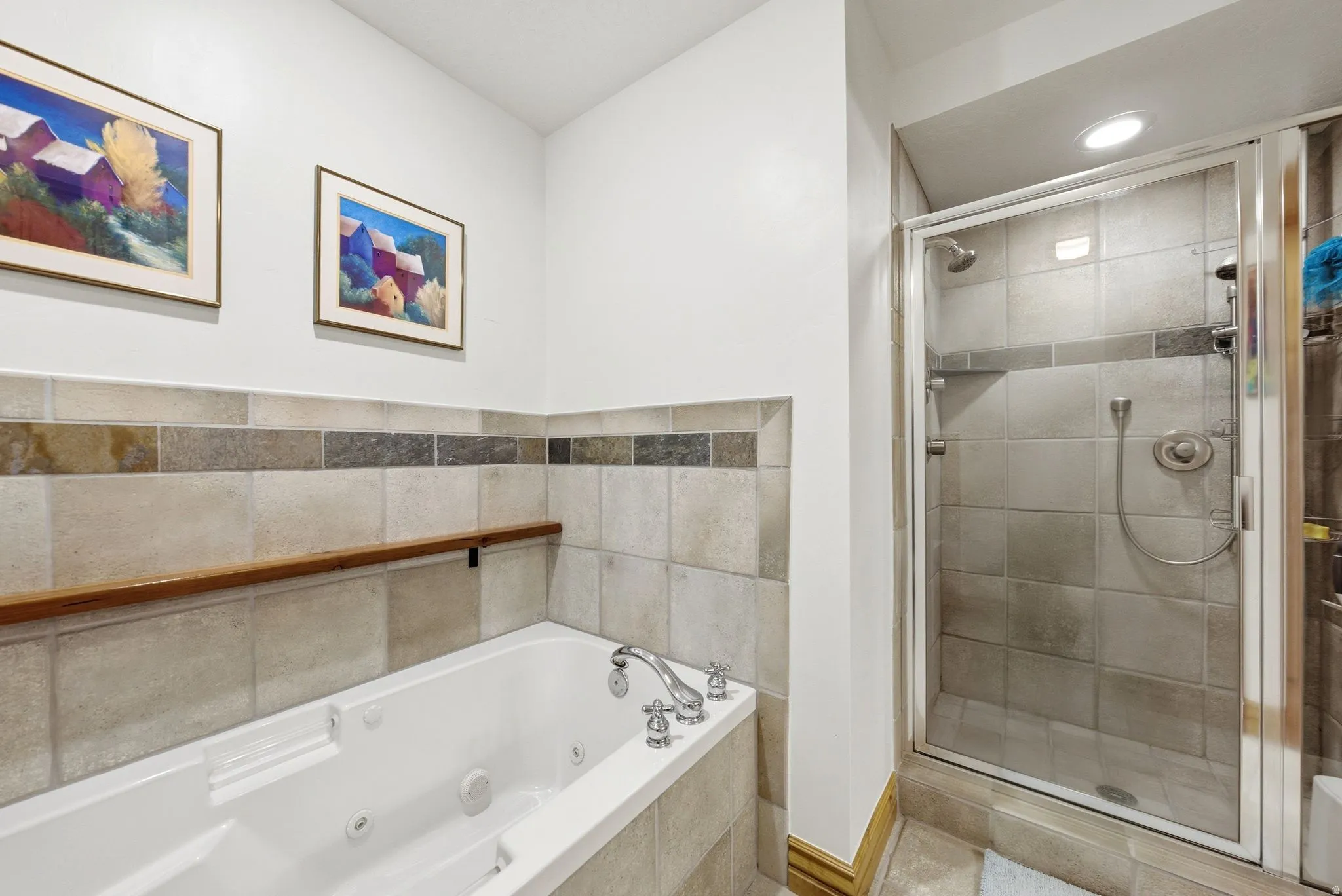 Bathroom featuring a white jetted tub with chrome fixtures, a tiled surround, and a glass-enclosed shower with a tiled interior