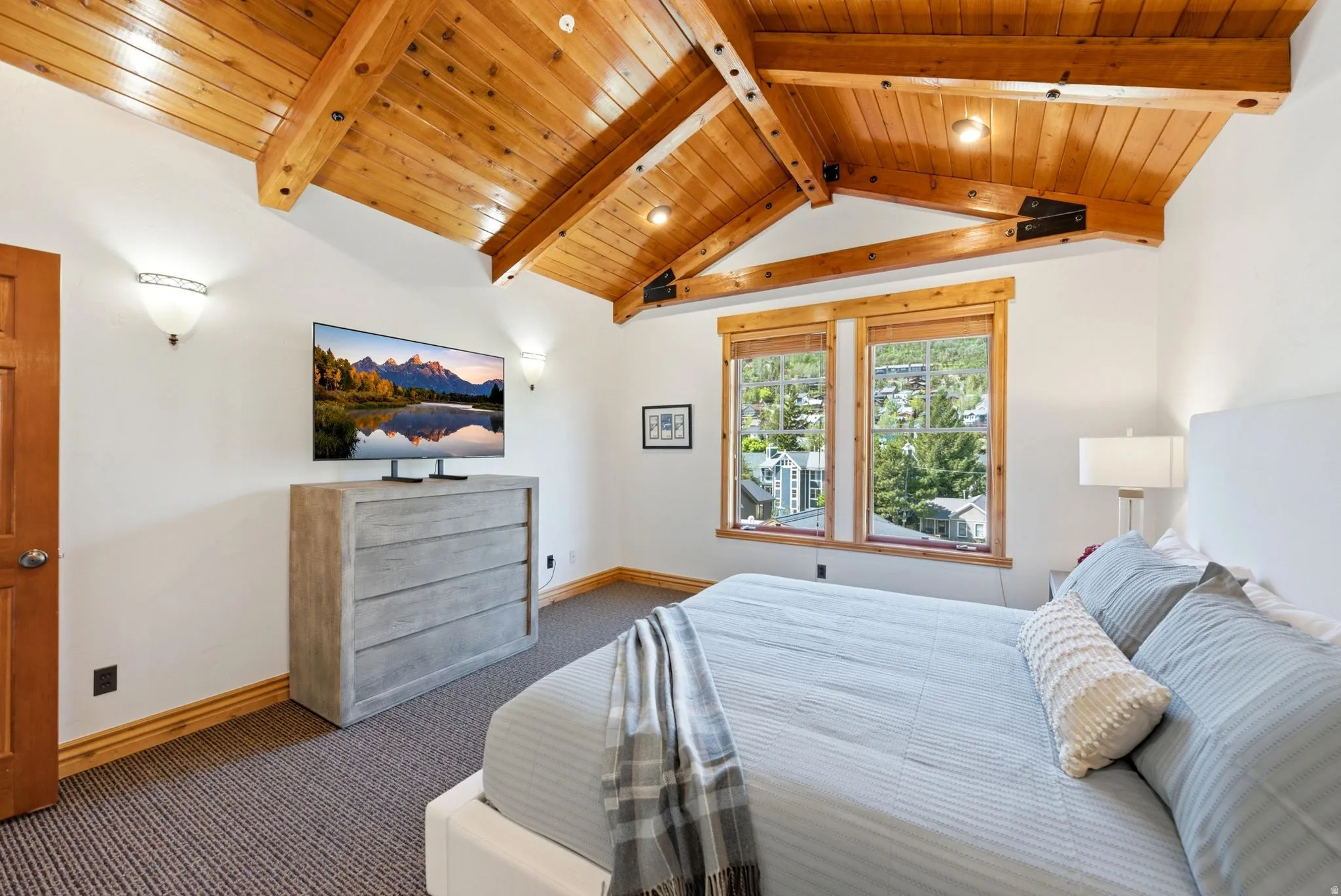 Vaulted wood-plank ceilings with exposed beams, white walls, and wood-trim windows