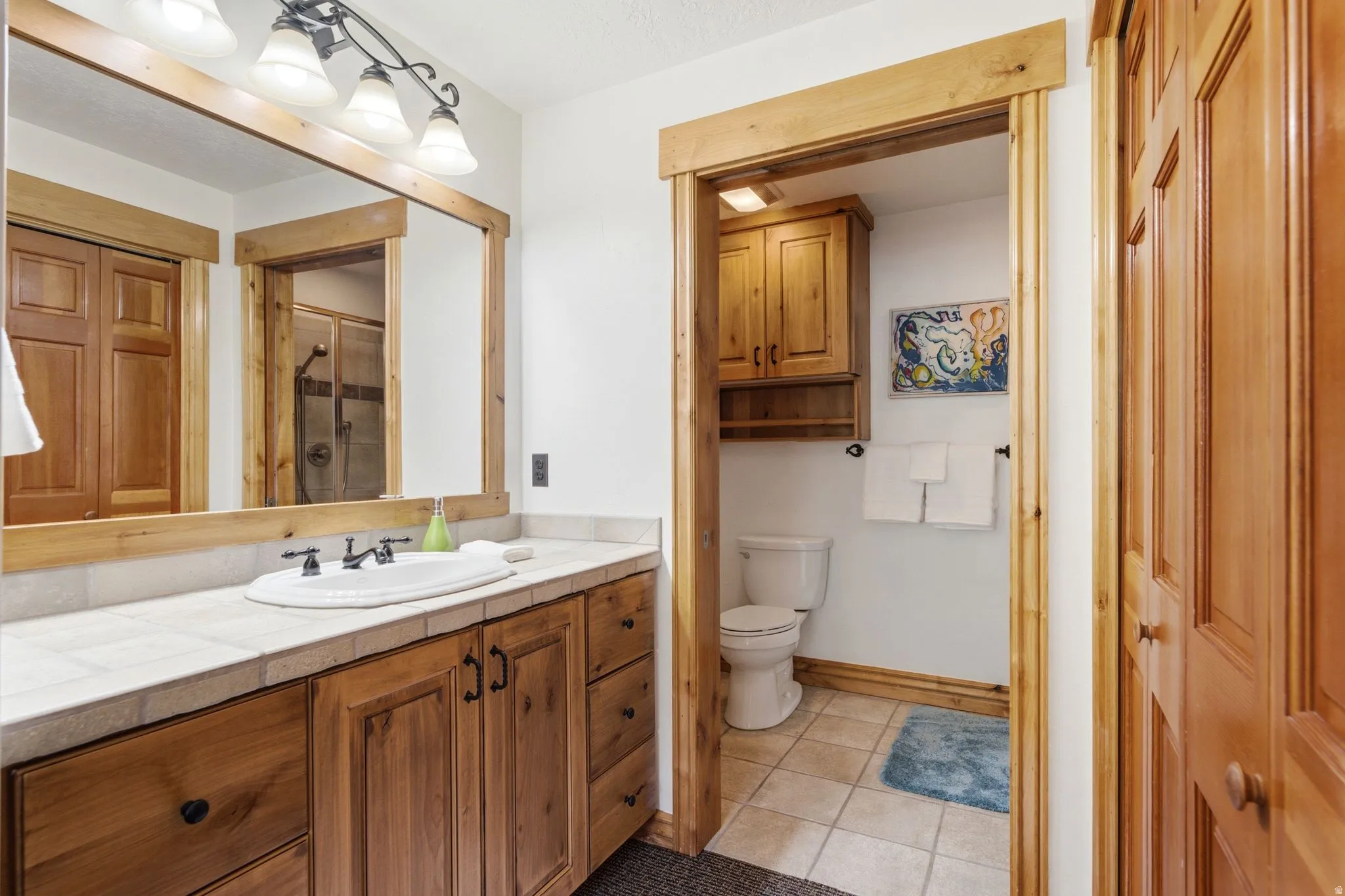 Bathroom featuring a wood-finish vanity with an integrated sink and tiled countertop