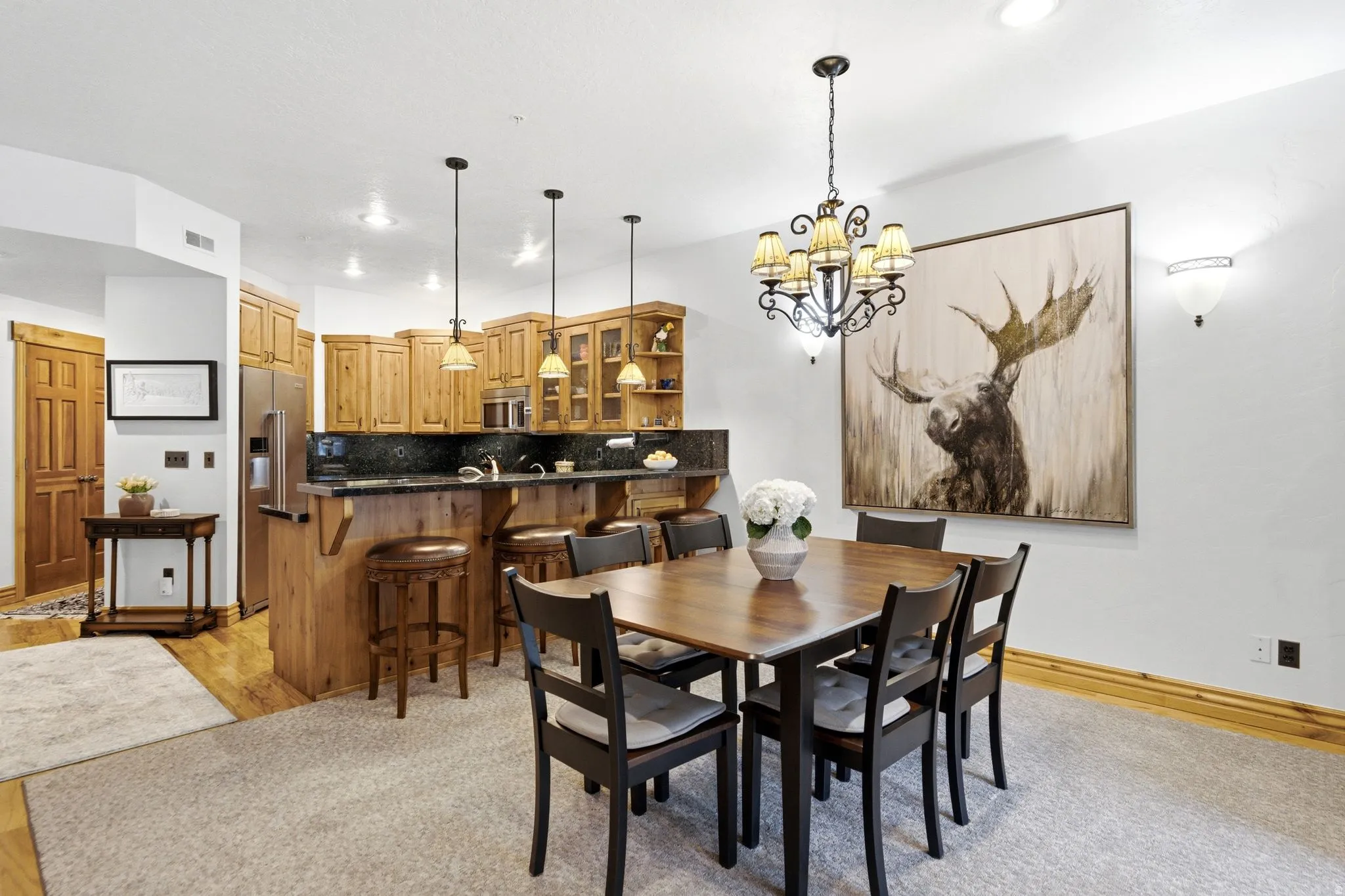 Open-concept dining area featuring a dark wood dining table with seating for six, illuminated by a decorative chandelier
