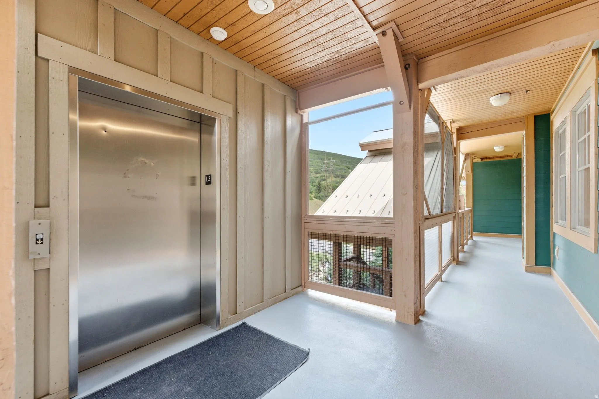 Stainless steel elevator door with a wood-paneled ceiling and light-colored flooring