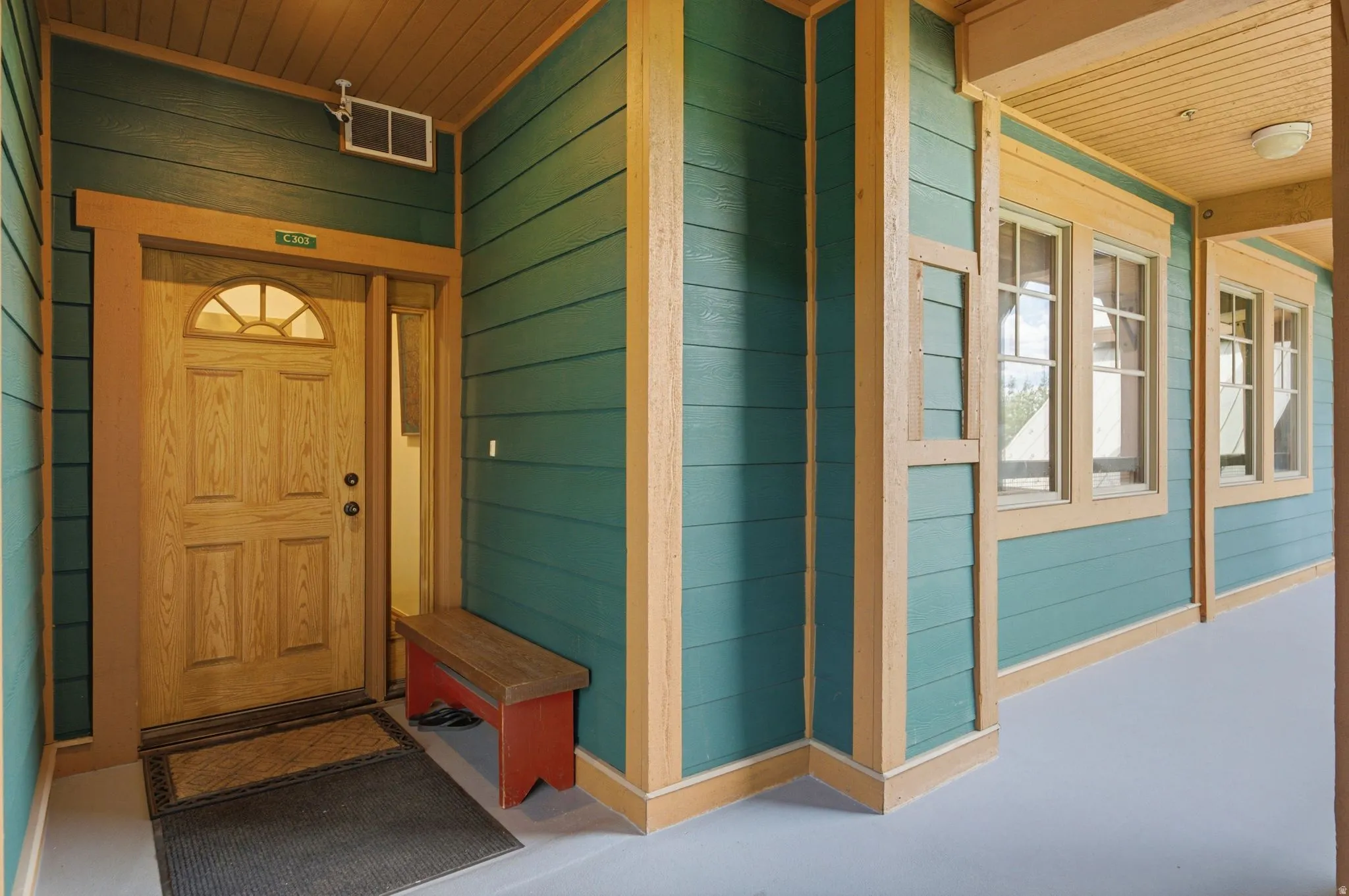 Entryway featuring a natural wood-finish door with an arched transom window, a side light panel, and durable teal horizontal siding