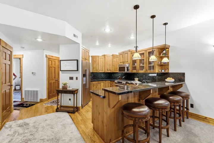 Kitchen area featuring light wood cabinetry, dark stone countertops, and stainless steel appliances