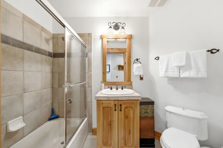 Bathroom featuring a light wood-finish vanity with a drop-in sink and a light-toned countertop