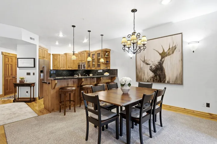 Open-concept dining area featuring a dark wood dining table with seating for six, illuminated by a decorative chandelier