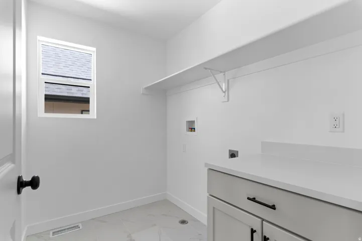 Laundry room with white walls, a single window, and a white floating shelf