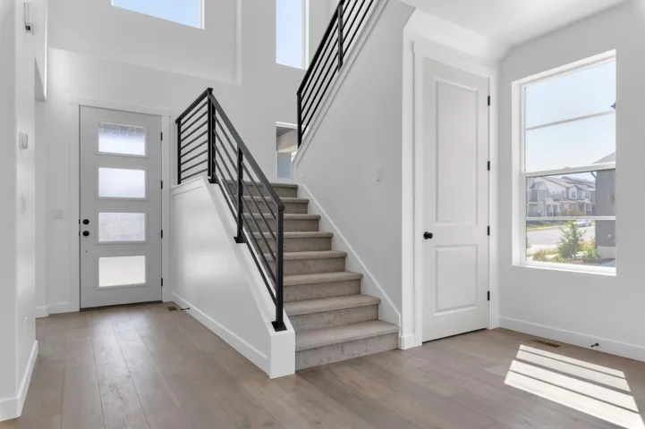 Two-story entryway featuring wood-finish flooring and a modern staircase with dark metal railings