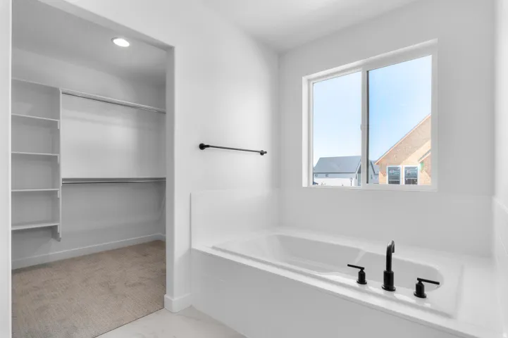 Soaking tub with matte black fixtures, set under a large window
