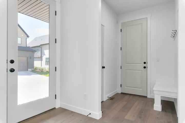 Entryway featuring wood-finish flooring, white trim, and a built-in bench with coat hooks