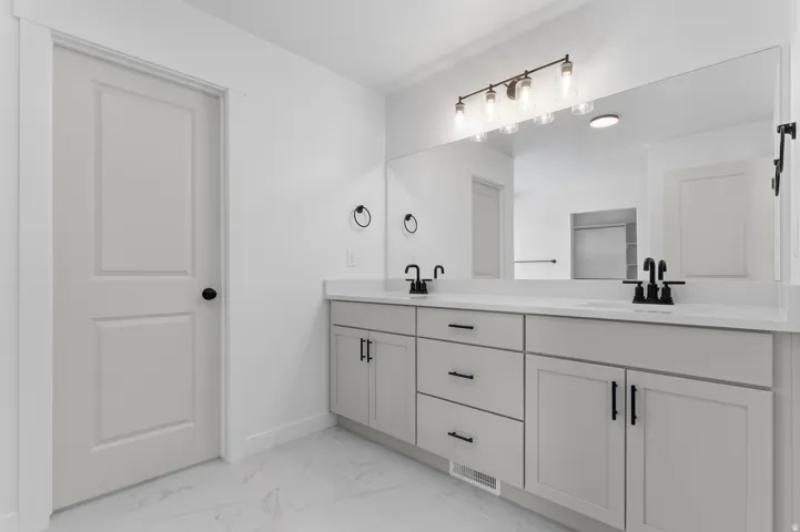 Double vanity featuring white countertops, undermount sinks, and matte black fixtures