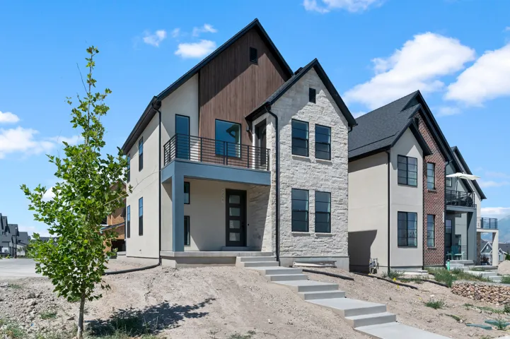Contemporary facade featuring light-colored stucco, stone veneer, and wood-finish siding