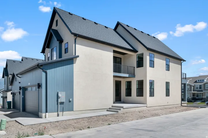 Modern multi-story property featuring a stucco exterior, dark shingle roof, and a blue vertical siding accent