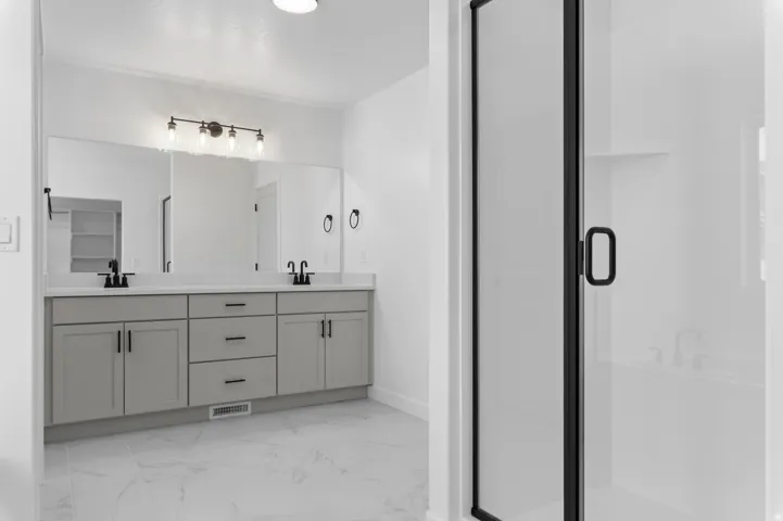 Contemporary bathroom featuring a double vanity with grey cabinetry, white countertops, and matte black hardware