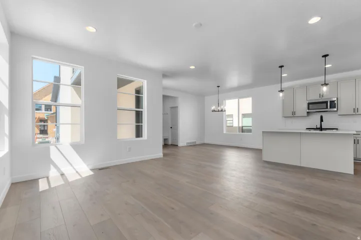 Open-concept living space featuring wood-finish flooring, recessed lighting, and multiple windows
