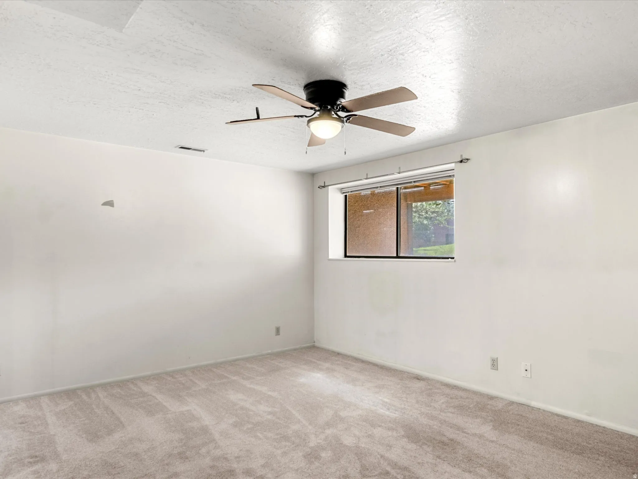 Carpeted room featuring a ceiling fan with integrated lighting, a single window, and textured walls