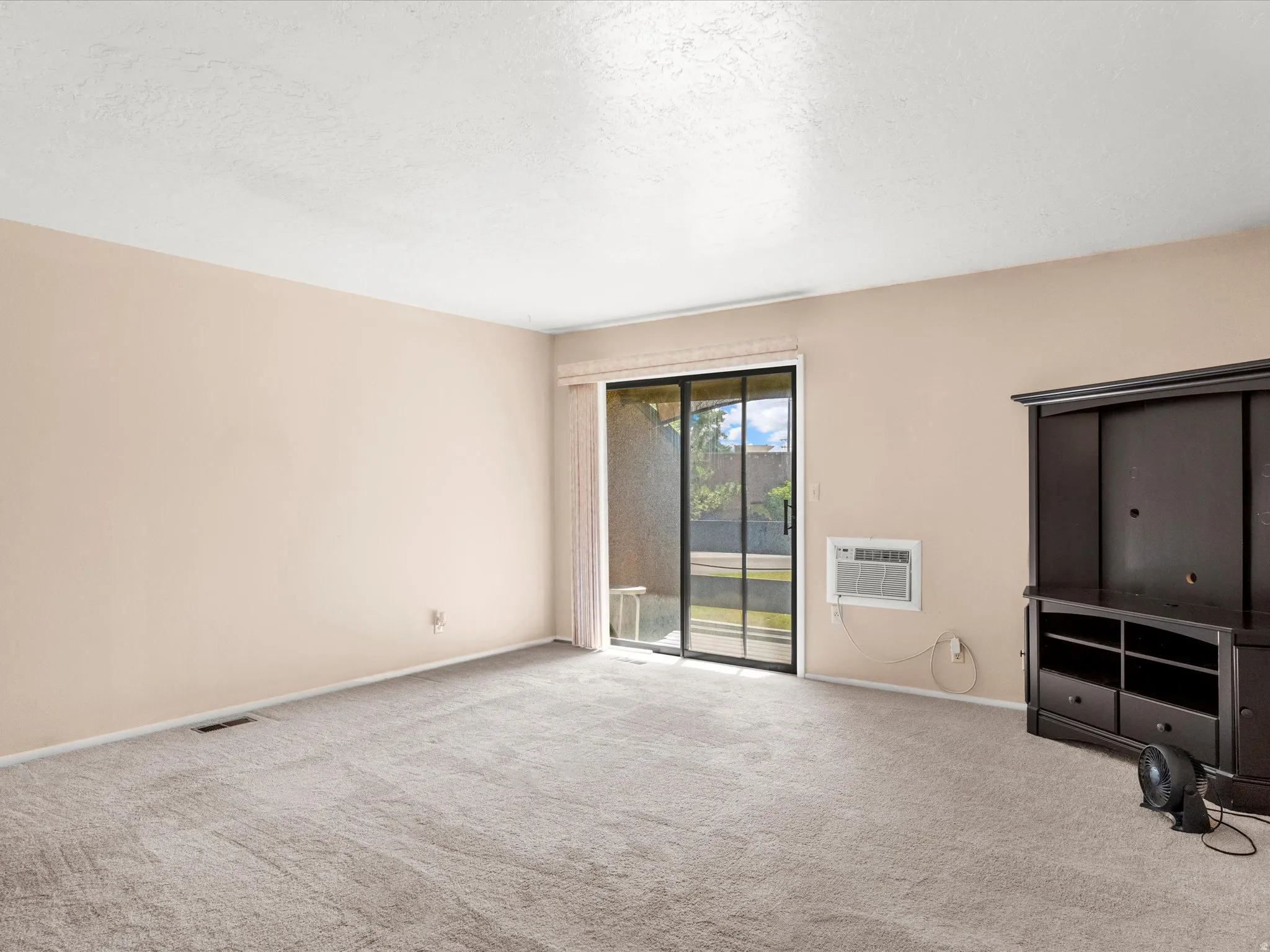 Carpeted living space with neutral painted walls and a sliding glass door