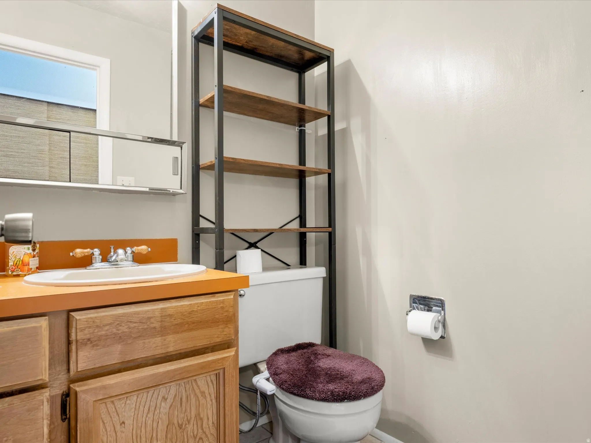 Bathroom vanity with wood-finish cabinetry, a white oval sink, and a contrasting orange countertop
