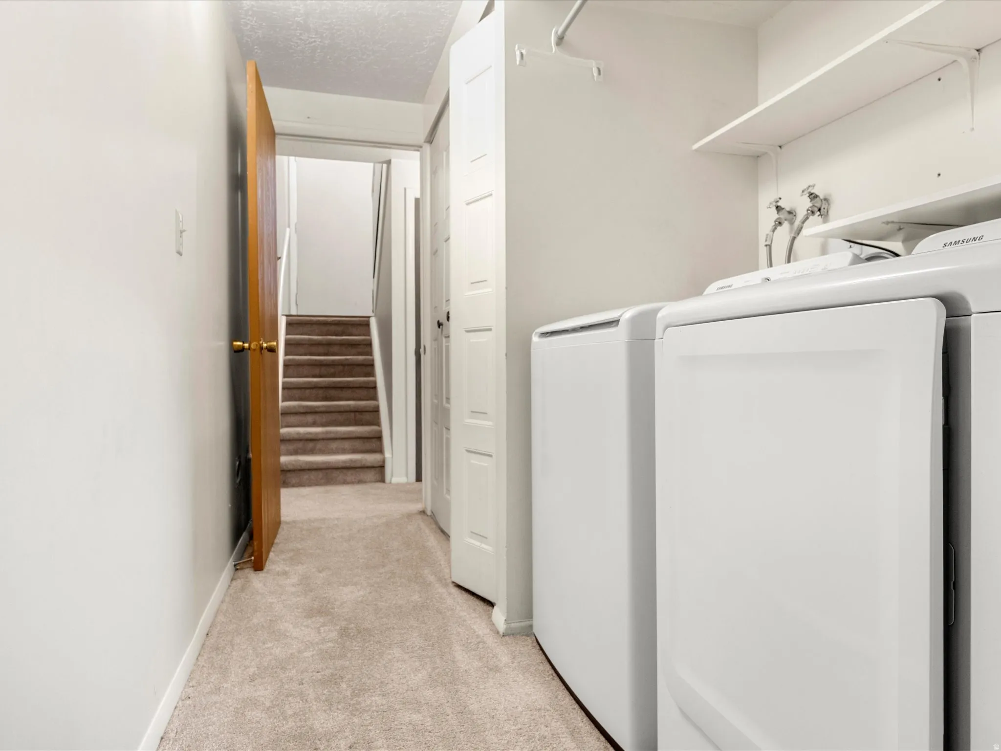 Dedicated laundry area featuring a washer and dryer, integrated shelving, and a hanging rod