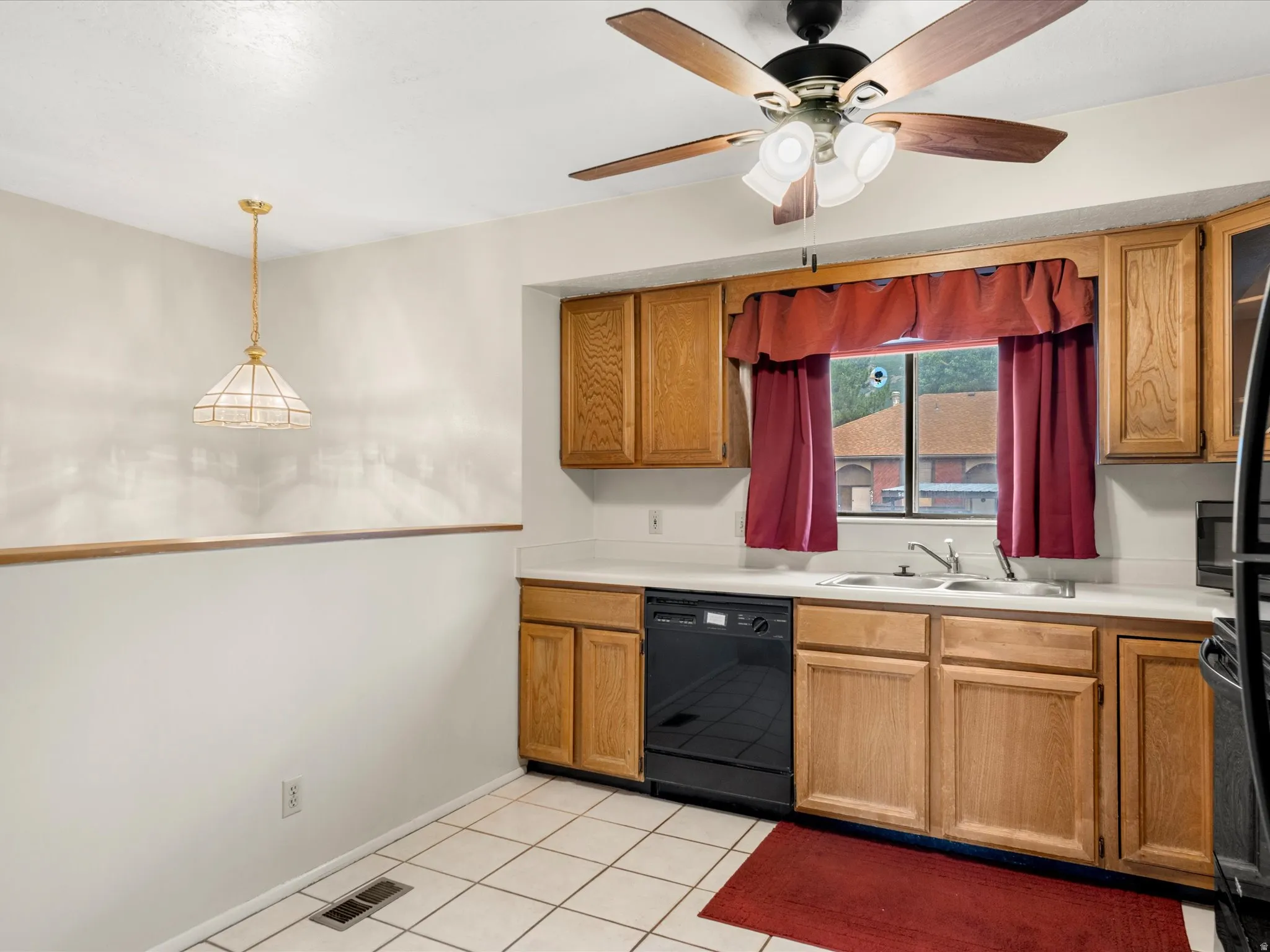 Kitchen area featuring wood cabinetry, white countertops, tile flooring, and a ceiling fan with integrated lighting
