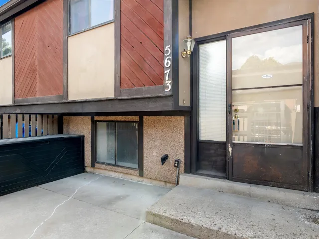 Multi-level exterior featuring concrete steps, an entry door with sidelight, and an attached garage with a black door
