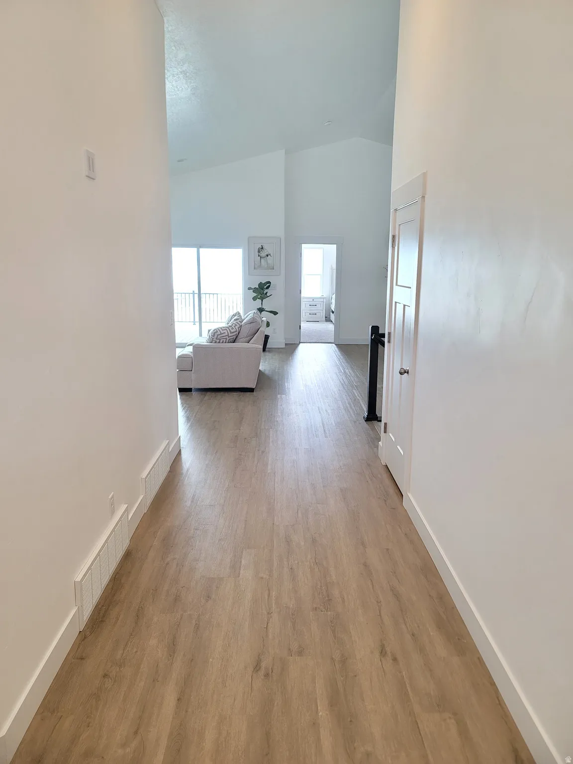Hallway featuring wood-finish flooring, white baseboards, and a neutral color palette