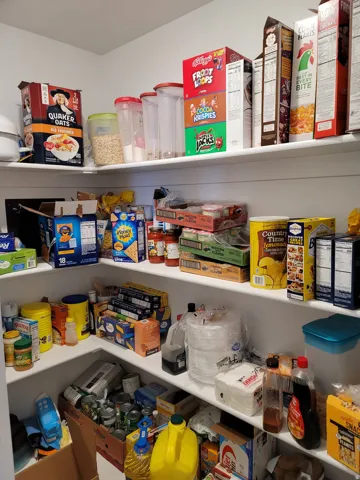 Corner pantry featuring multiple white shelves