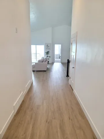 Hallway featuring wood-finish flooring, white baseboards, and a neutral color palette