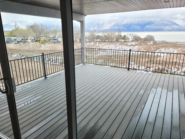 Spacious outdoor deck featuring composite decking, black metal railings, and a sliding glass door