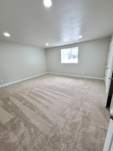 Spacious room featuring neutral carpeting, recessed lighting, a single window, and light-toned wall paint